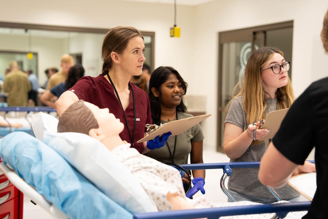 A medical student assesses a mannequin in a simulation lab.